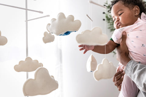 A baby reaches for Sky, a cloud baby mobile from Happiest Baby
