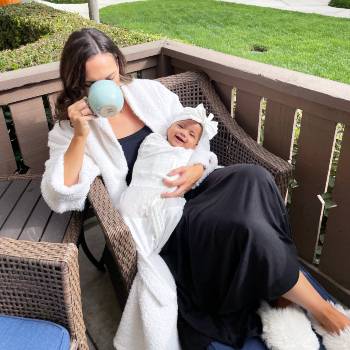 Mom drinking coffee with happy baby in Sleepea swaddle