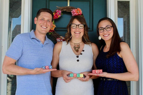 Family posing with baby blocks to announce surrogacy pregnancy