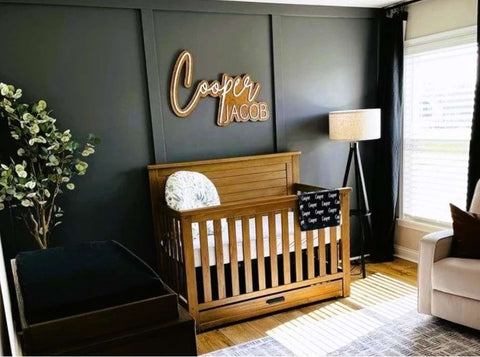Baby nursery with a black wall, wooden crib, and neutral accents