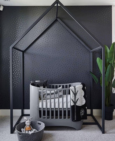 Baby nursery that has black wallpaper with reflective black dots