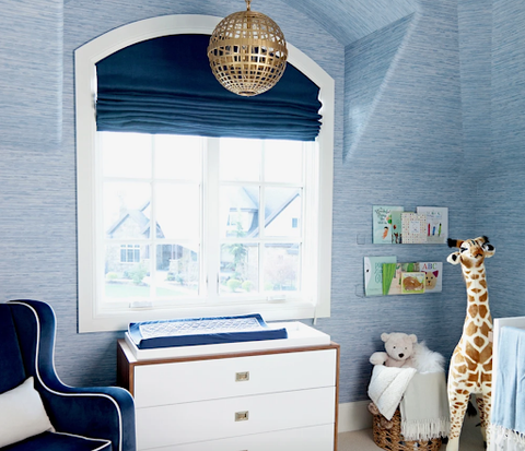 A pale blue baby nursery with dark blue window shades.