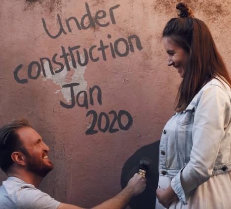 Woman standing in profile next to wall with pregnancy bump painted behind her