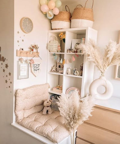 Neutral toddler nook with a cozy reading bench and bookshelves.