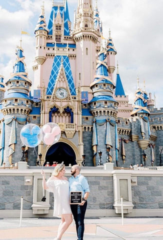 A Disney pregnancy announcement photo taken in the Magic Kingdom with balloons