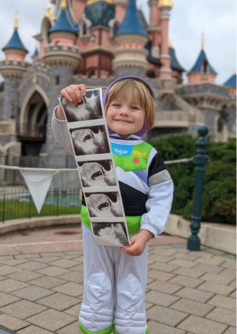 A big-brother-to-be is dressed as Buzz Lightyear and holds an ultrasound photo to announce a pregnancy at Disney