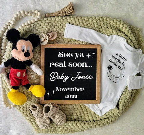 Disney pregnancy announcement photo: A letterboard that says "see ya real soon Baby Jones" placed next to a Mickey Mouse doll