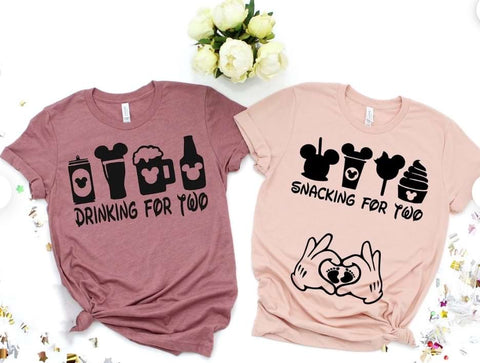 Two Disney pregnancy announcement t-shirts: one that reads "drinking for two" and one that reads "snacking for two" with silhouettes of Disney Parks foods and drinks