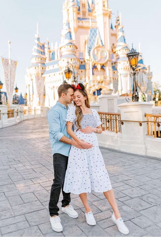 A couple poses in Disney's Magic Kingdom to announce a pregnancy