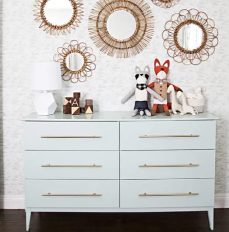 Light blue dresser with horizontal gold pulls in a nursery