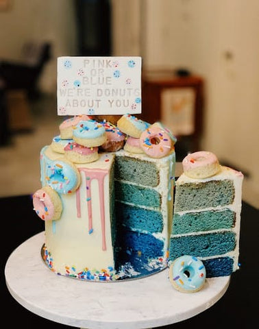 Gender reveal cake topped with donuts.