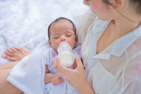 A mother feeds her newborn with a bottle