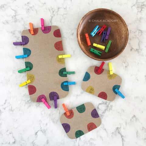 Colorful clothespins clipped onto colorful dots drawn onto cardboard.