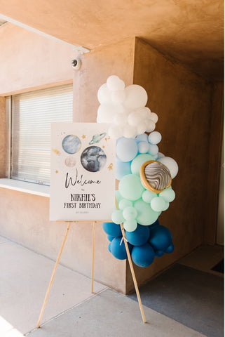 Balloons and sign welcoming guests to a space-themed first birthday party