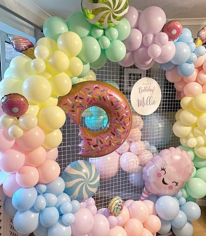 Pastel-colored first birthday balloon display featuring peppermint and donut-shaped mylar balloons.