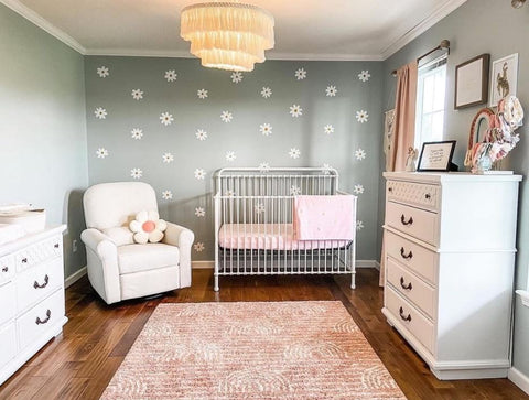 A floral baby nursery with daisies painted on the wall behind the crib