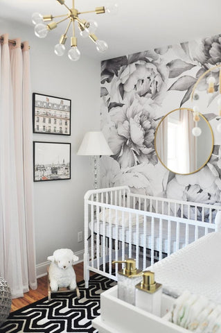 A modern-looking floral nursery with a bold print rug and black and white flower wallpaper