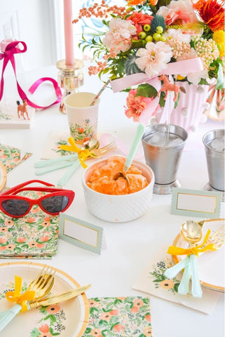 Table decorated with bright flower-themed decor for a summer baby shower