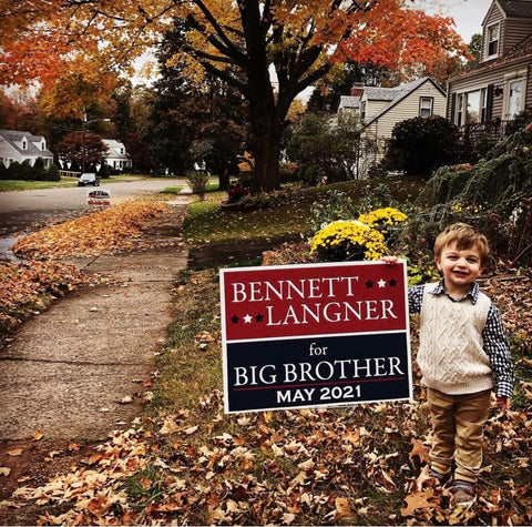 Toddler boy poses in front of election sign that says "Bennet Langer Big Brother May 2022"