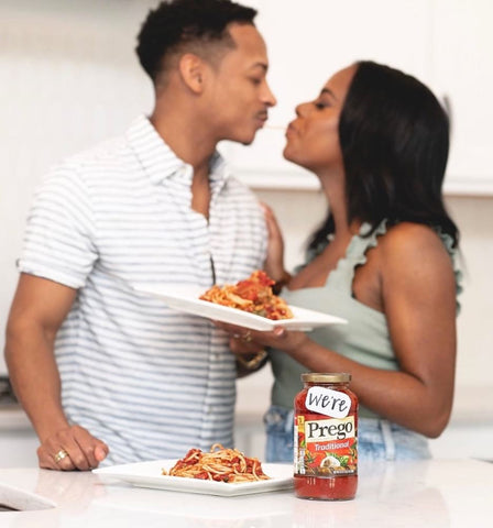 A couple kisses behind a jar of Prego pasta sauce to announce a pregnancy