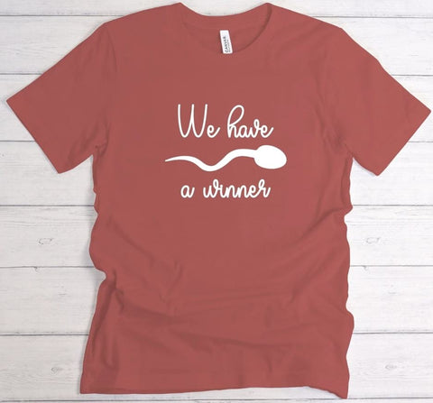 Pregnancy announcement t-shirt that says "We Have a Winner" with the illustration of a sperm