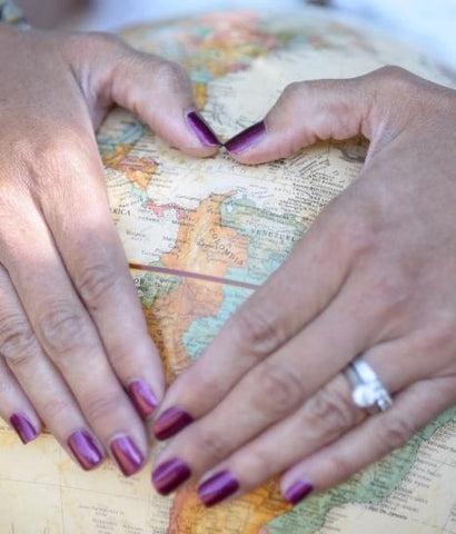 Hands held in a heart shape over a globe