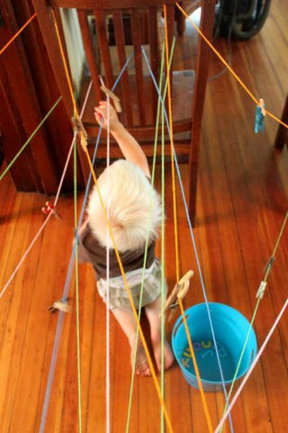 Toddler tries to get through maze made with string.