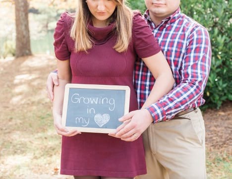 Couple holds chalkboard that says "growing in my heart"