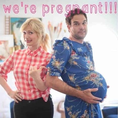 Woman standing next to a man with fake pregnant belly to announce pregnancy
