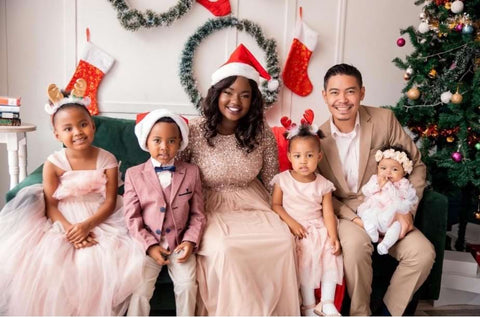 A family wears formal attire and festive accessories in a holiday card photo