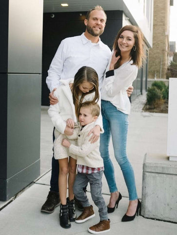 A family dressed in coordinated outfits pose for a holiday card photo