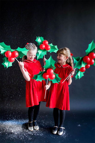 Two girls pose with DIY holly (made from balloons) for a holiday card photo