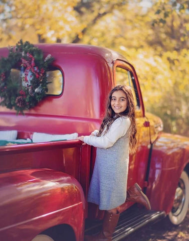 A girl poses with a vintage truck for a holiday card photo