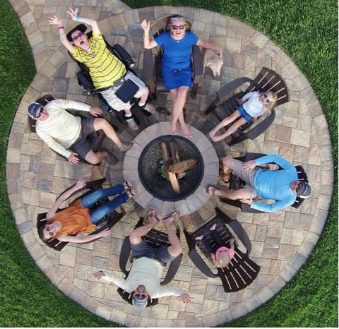An aerial holiday photo captures a family gathered around an outdoor fireplace 