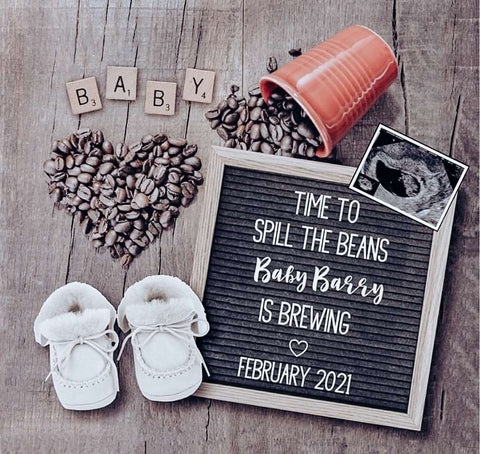 A letterboard pregnancy announcement that says "time to spill the beans" photographed near coffee beans