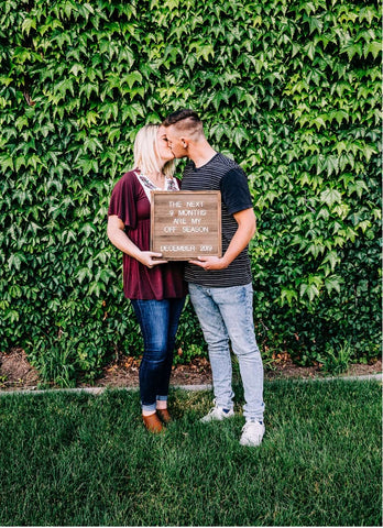 A couple holds a baseball-themed letterboard pregnancy announcement