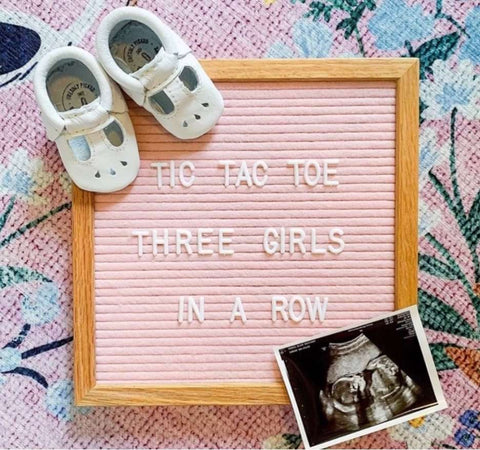 A pink letterboard pregnancy announcement that says "tic tac toe three girls in a row"