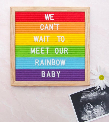 A rainbow letterboard pregnancy announcement
