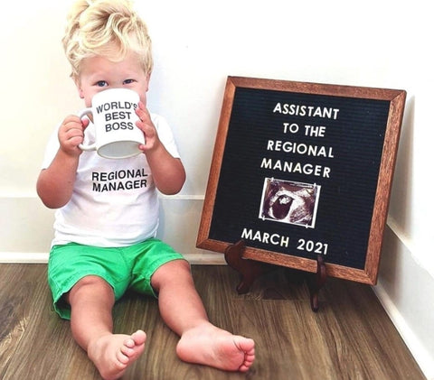 A toddler poses next to a letterboard pregnancy announcement