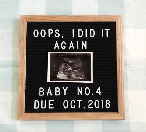 A letterboard pregnancy announcement that says "Oops I did it again baby no. 4 due October"