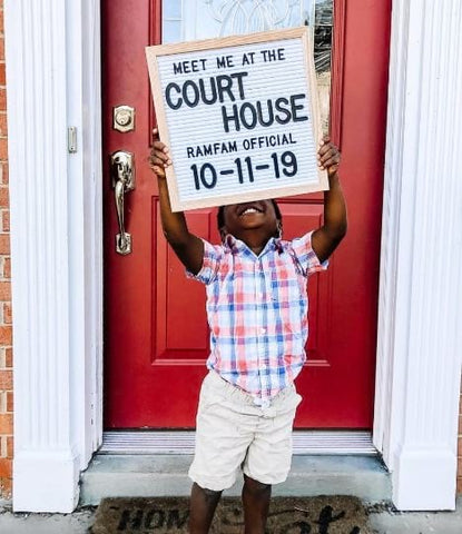 Little boy holds a letterboard announcing that his adoption was made official