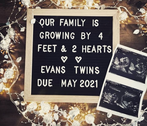 A letterboard that says "our family is growing by 4 feet and 2 hearts" to announce a twin pregnancy