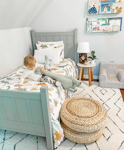 Toddler room with a mint color scheme and dinosaur bedding.