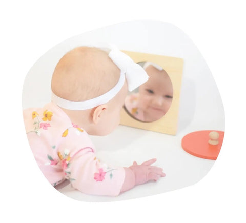 Baby looks at a Montessori-style mirror toy