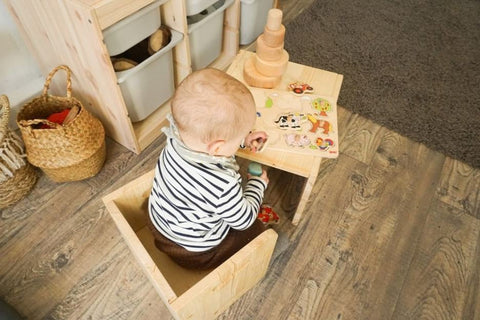 A baby plays at a child-sized desk in a Montessori nursery