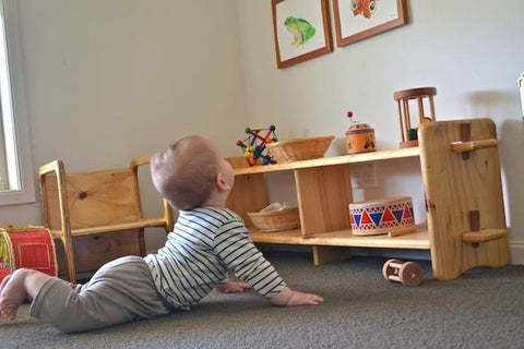 A baby gazes at low-hung pictures from the floor