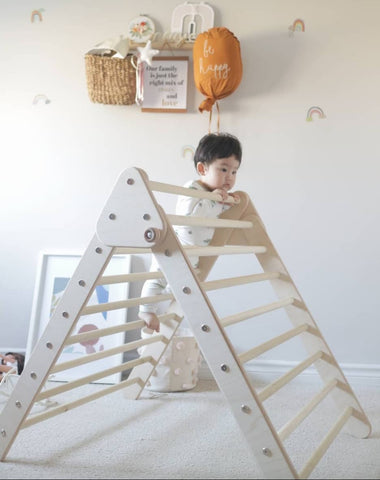 Baby climbs a Pikler triangle structure in a Montessori-style nursery