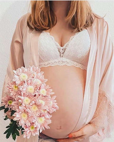 Mother's Day pregnancy announcement featuring a woman's pregnant belly and bouquet of flowers