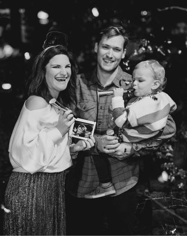 A family poses with an ultrasound on New Year's to announce a pregnancy