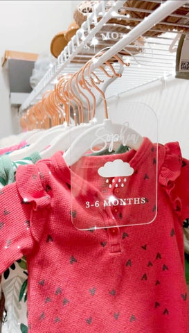 Baby clothes hanging in a nursery closet with acrylic dividers